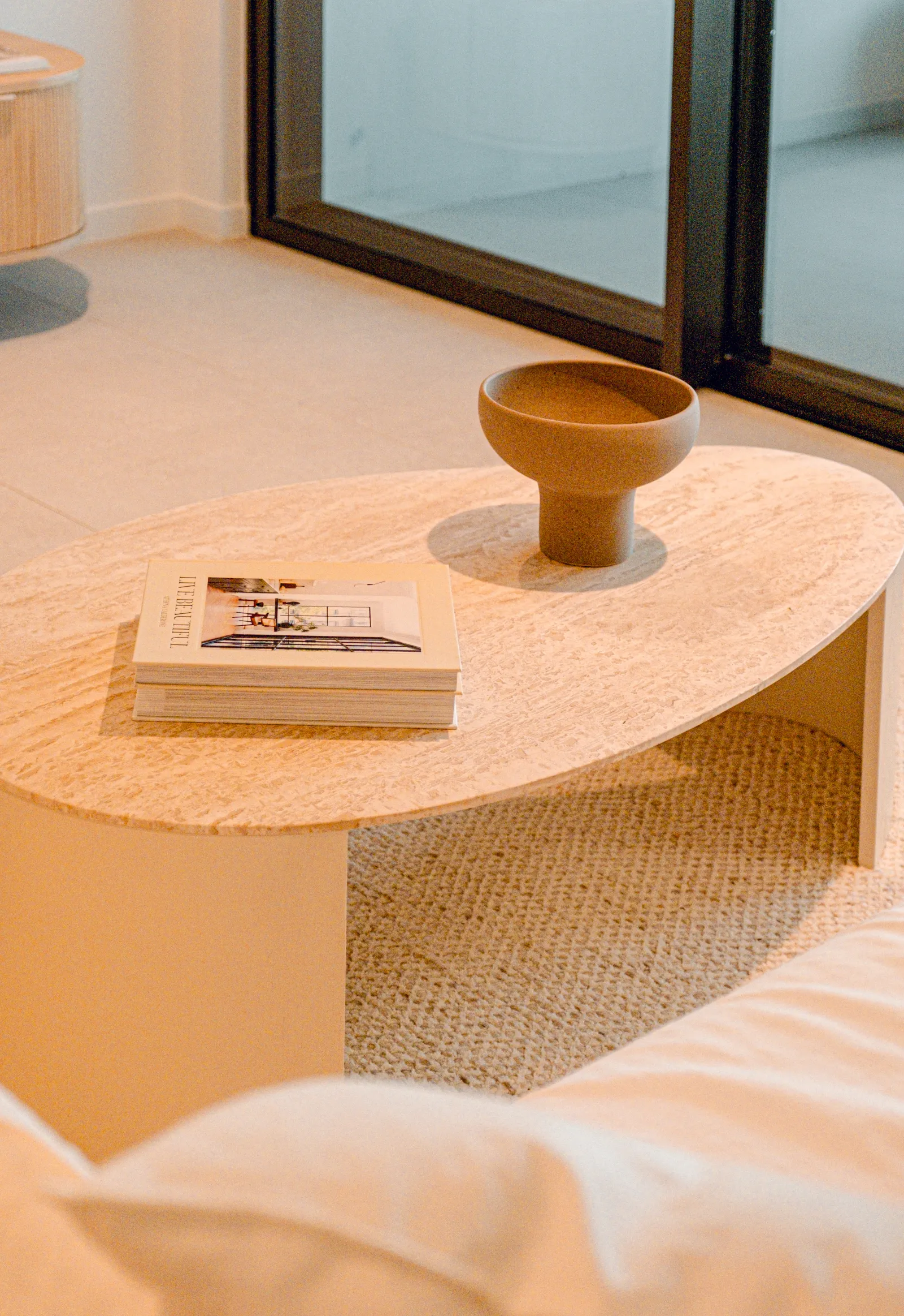 Minimalist living room with round marble coffee table and neutral-toned furnishings.