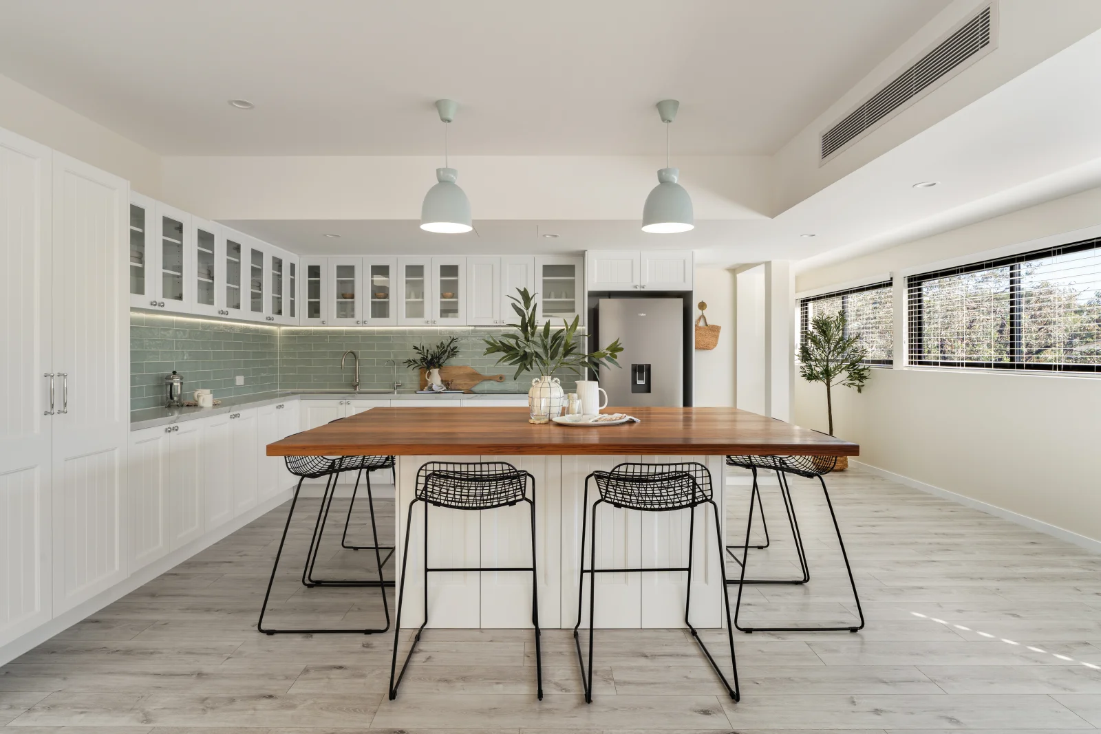 Modern open-concept kitchen with white cabinetry, wooden island, and minimalist design.