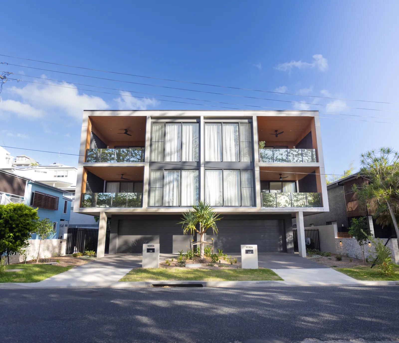 Modern two-story luxury home with large windows, spacious balcony, and lush surroundings.